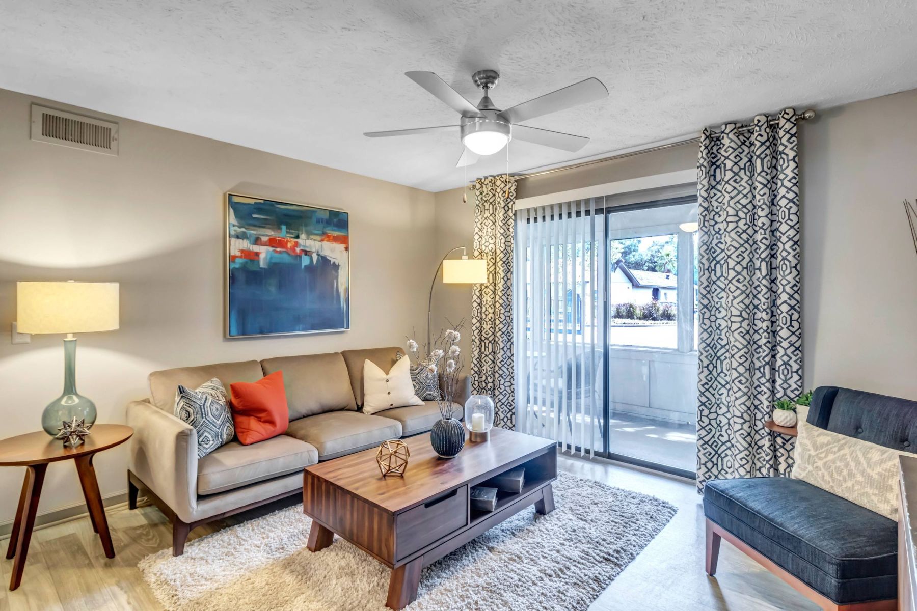 Empty room with wood floors, ceiling fan, and sliding glass door leading to a patio with vertical blinds at Apex West Midown.